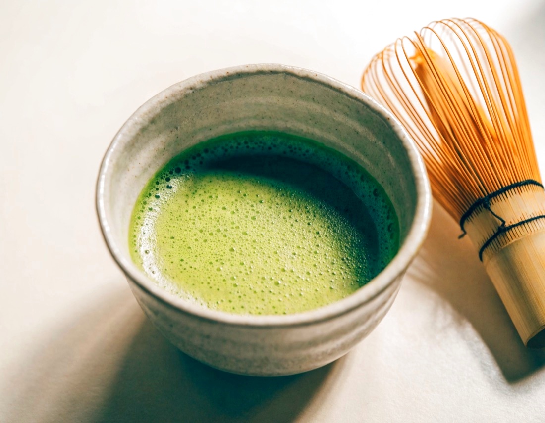Whisked matcha in a bowl with a bamboo whisk