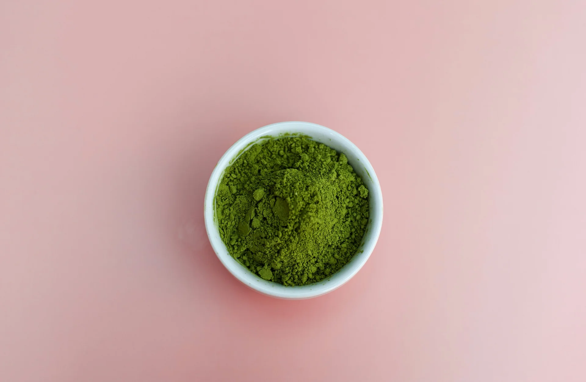 A small white bowl of bright green matcha powder